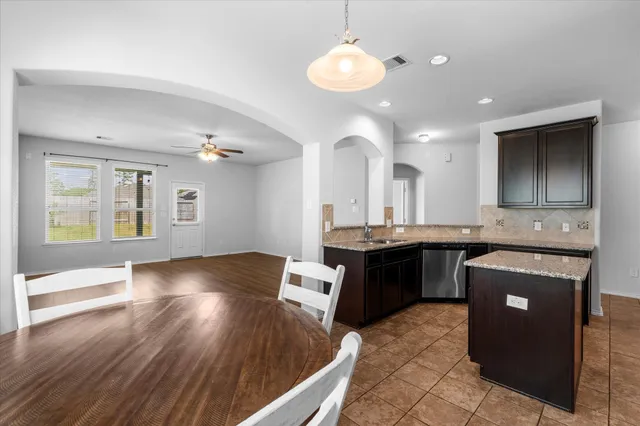 a large kitchen with a large counter top space a sink stainless steel appliances and cabinets