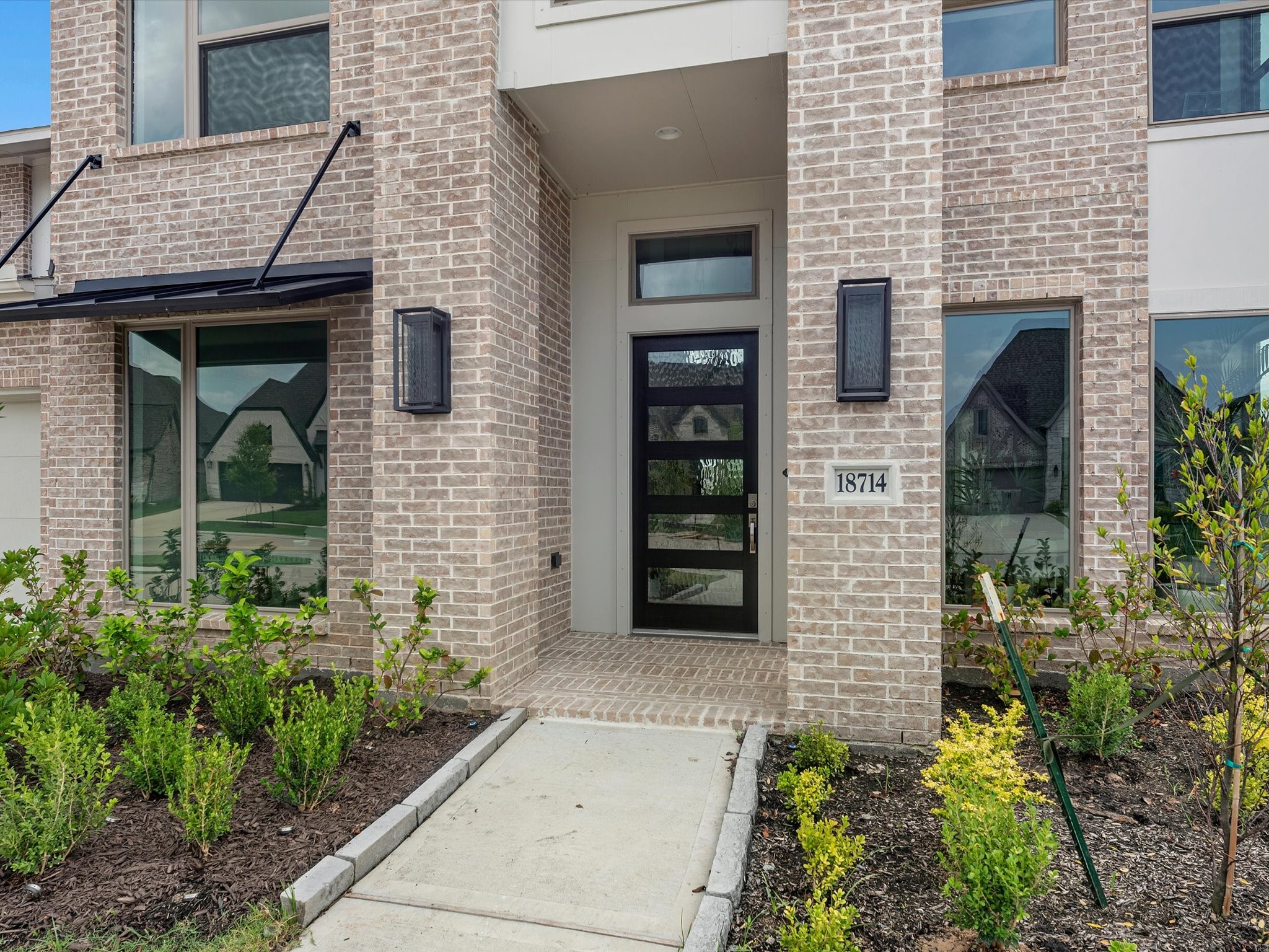 18714 Pistachio Way Manvel, TX 77578 - Photo 4 of 48 A welcoming covered entry features elegant coach lighting and a glass-paneled front door that fills the foyer with natural light.