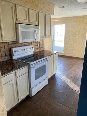 a kitchen with granite countertop white cabinets and white appliances