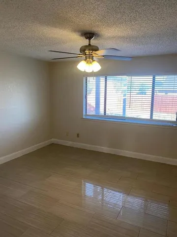 an empty room with a window and a ceiling fan