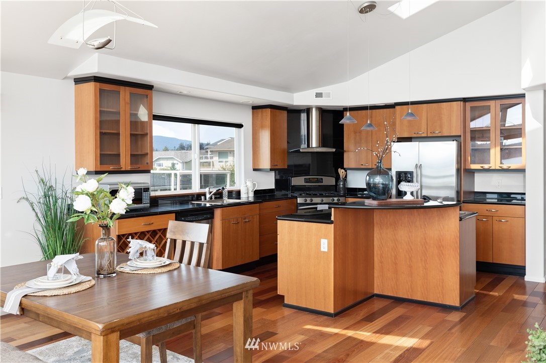4913 Dundee Drive Anacortes, WA 98221 - Photo 14 of 40 a living room with stainless steel appliances granite countertop a couch a dining table and chairs with wooden floor