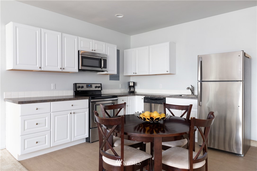 4913 Dundee Drive Anacortes, WA 98221 - Photo 30 of 40 a kitchen with stainless steel appliances a white table and chairs in it