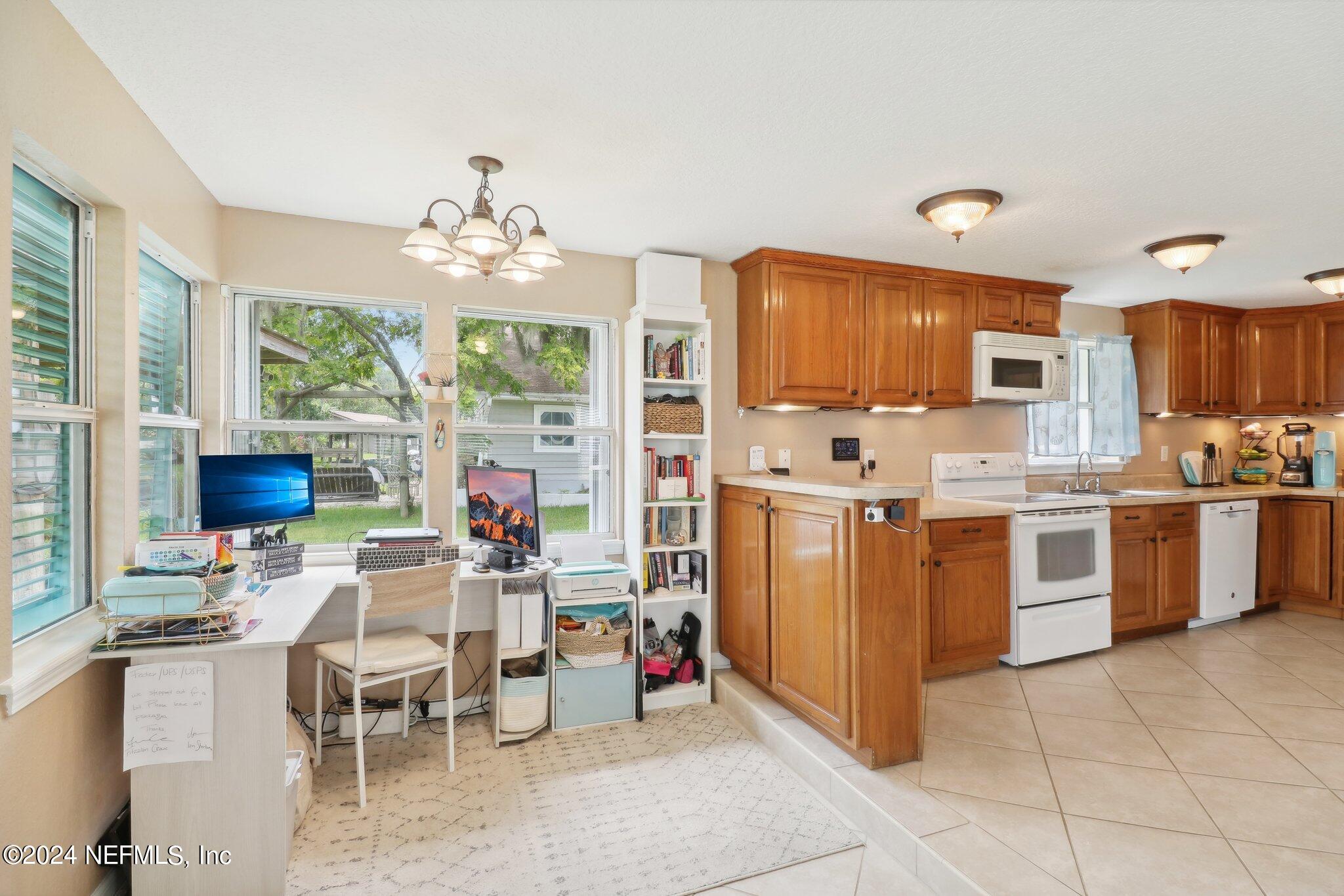 2870 Adams Road St. Augustine, FL 32092 - Photo 21 of 31 a kitchen with stainless steel appliances kitchen island granite countertop a stove top oven a sink dishwasher and a dining table with wooden floor