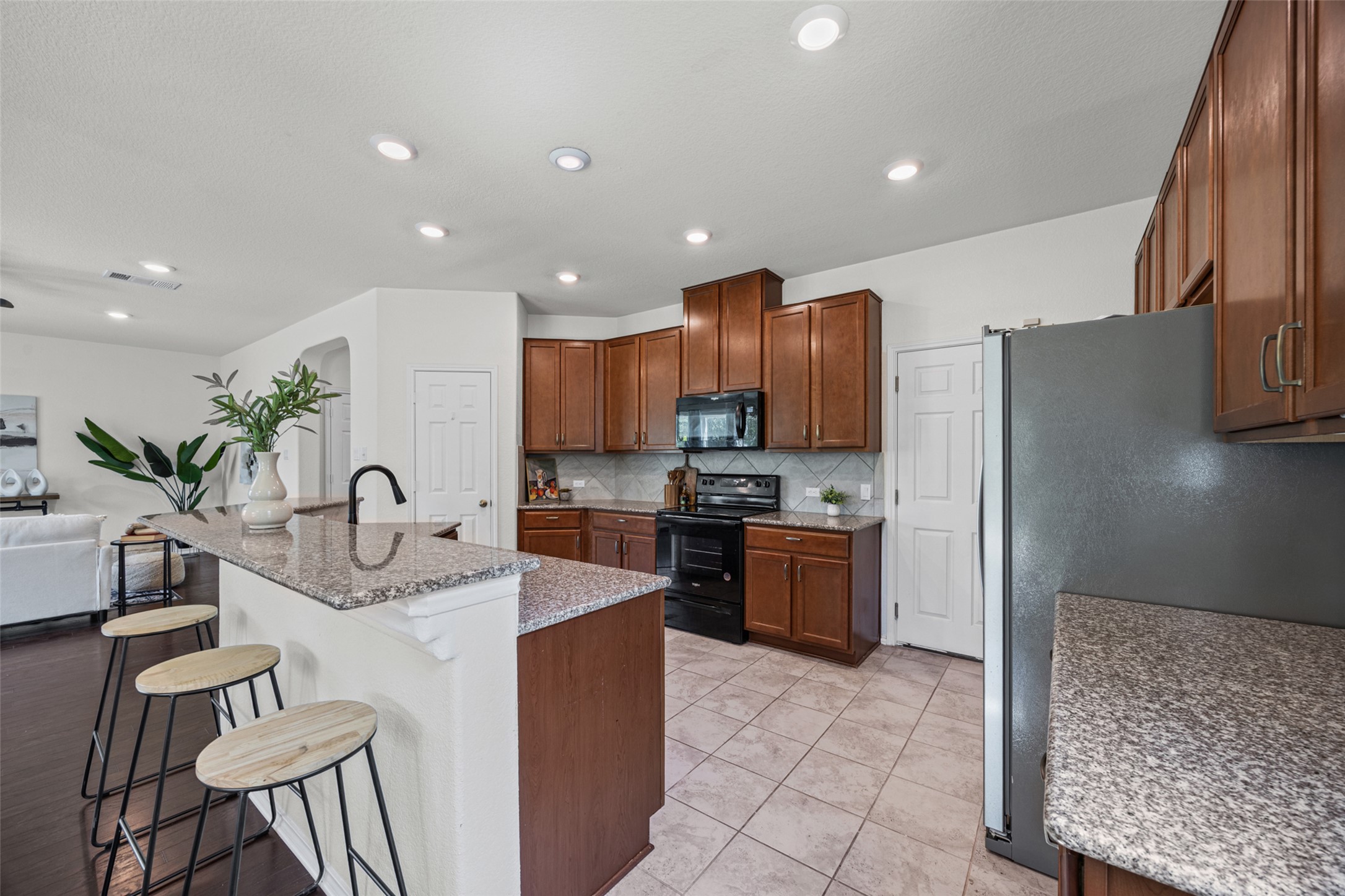 2471 Sunrise Road, Unit 64 Round Rock, TX 78664 - Photo 7 of 32 Granite counters and rich wood cabinetry define this modern kitchen, offering both elegance and utility.