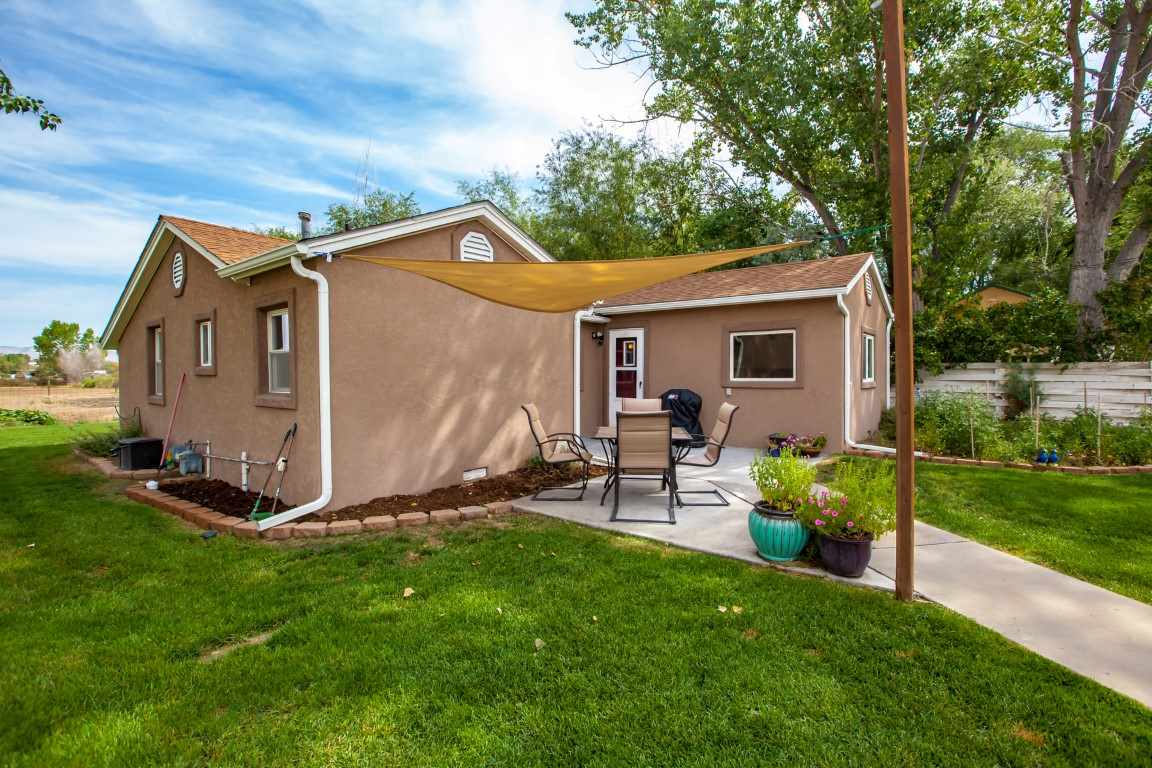2390 H Road Grand Junction, CO 81505 - Photo 30 of 42 a backyard of a house with table and chairs plants and large tree