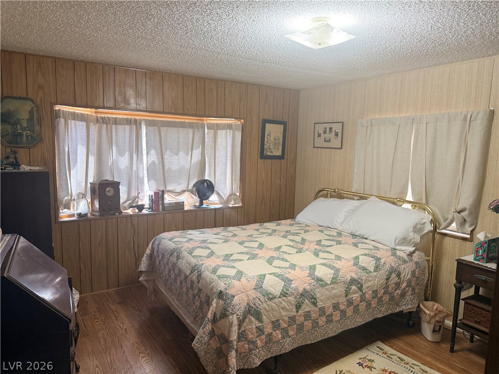 1391 West Dyer Road Pahrump, NV 89048 - Photo 13 of 50 A well-lit bedroom features durable laminate flooring and wood-paneled walls, offering a quaint and cozy retreat.