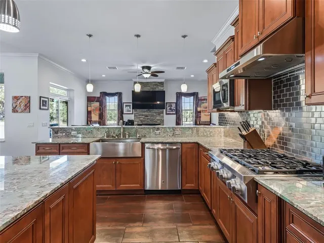 a kitchen with stainless steel appliances granite countertop a stove top oven a sink dishwasher a dining table and chairs