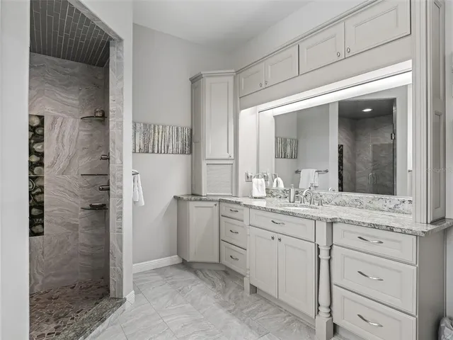 a bathroom with a granite countertop sink mirror and shower