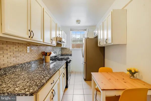 a kitchen with granite countertop a sink a stove and a refrigerator