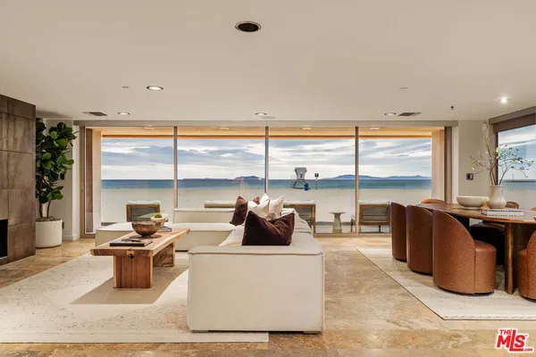 a living room with furniture potted plant and large windows