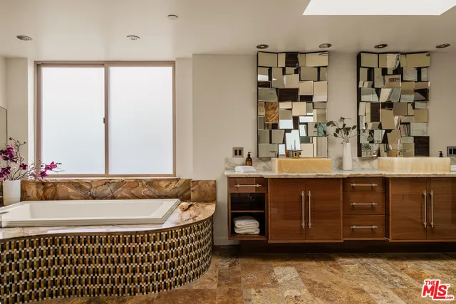 a spacious bathroom with a tub sink and mirror