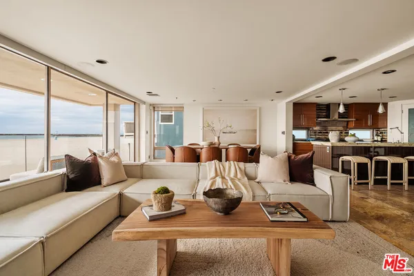 a living room with furniture kitchen view and a large window