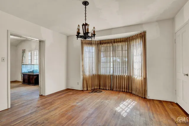 an empty room with wooden floor staircase and windows