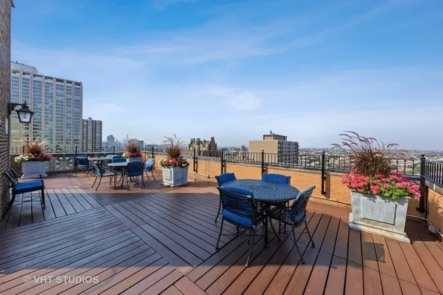 a view of a rooftop deck with chairs and wooden floor