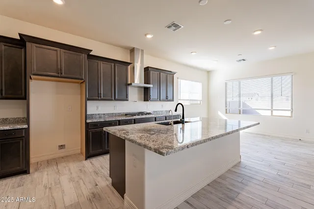 a large kitchen with stainless steel appliances kitchen island granite countertop a large counter top and wooden floors