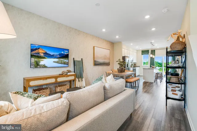 a living room with furniture kitchen view and a wooden floor
