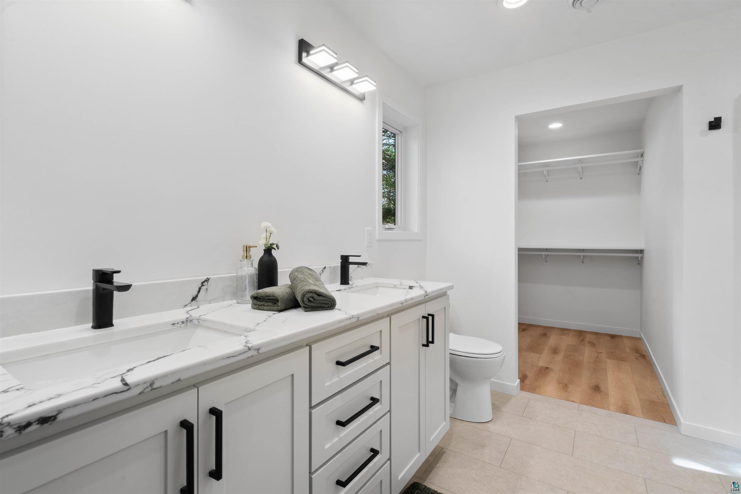 1386 Stephen Road Cloquet, MN 55720 - Photo 17 of 25 Double vanity featuring white cabinetry with matte black hardware, integrated rectangular sinks, and veined countertops