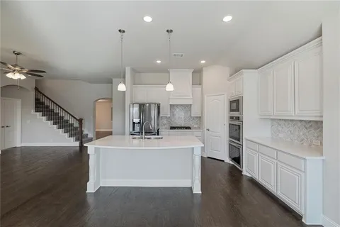 a large white kitchen with kitchen island a sink stainless steel appliances and cabinets