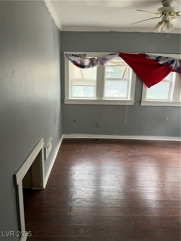Spare room featuring ornamental molding, dark wood-type flooring, and a ceiling fan