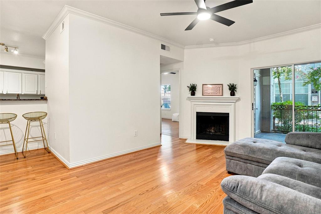 2601 Preston Road, Unit 4103 Plano, TX 75093 - Photo 4 of 16 Wood-finish flooring throughout, a built-in fireplace with mantel, crown molding, and a ceiling fan with integrated lighting
