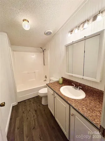a bathroom with a granite countertop sink a toilet a mirror and bathtub