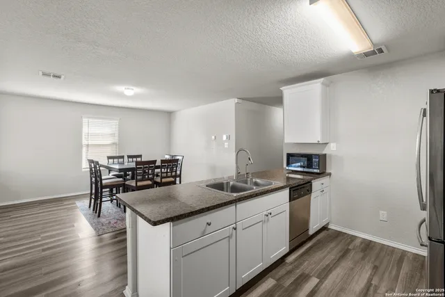 a kitchen with granite countertop a sink stove and refrigerator
