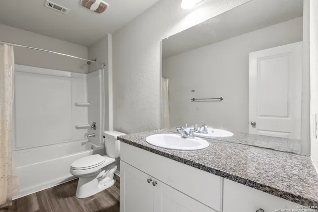 a bathroom with a granite countertop sink toilet a mirror and shower