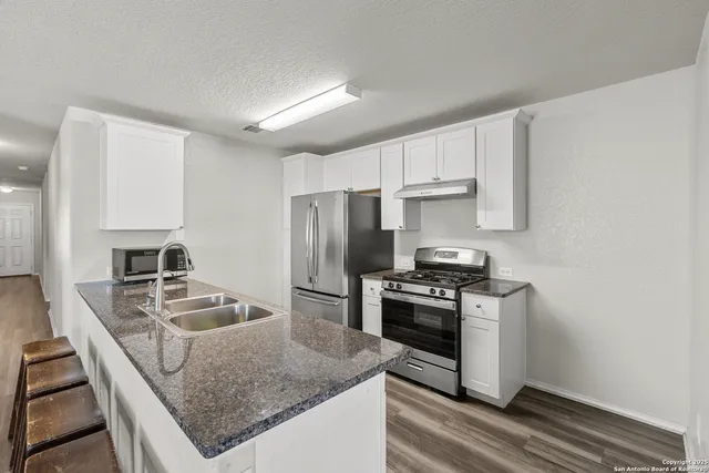 a kitchen with kitchen island granite countertop a stove sink and refrigerator