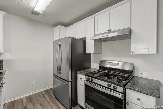 a kitchen with stainless steel appliances granite countertop a stove and a refrigerator