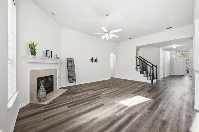 a view of an empty room with wooden floor fireplace and a window