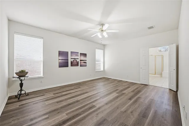 a view of empty room with wooden floor and fan