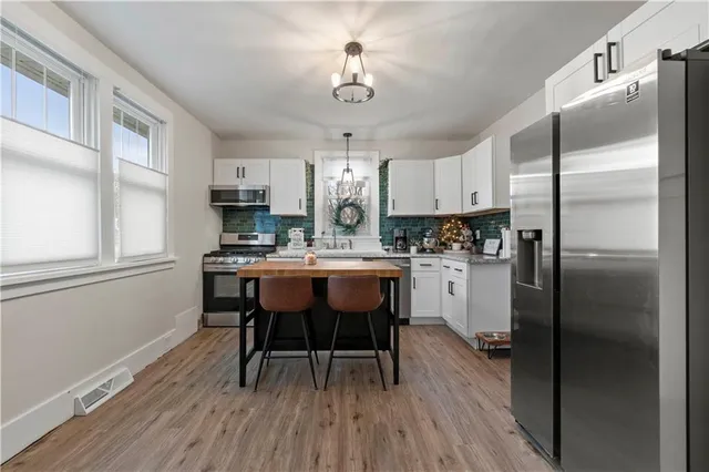 a kitchen with stainless steel appliances granite countertop a sink stove a refrigerator and a dining table with wooden floor