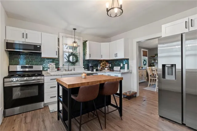 a kitchen with stainless steel appliances kitchen island granite countertop a dining table and chairs