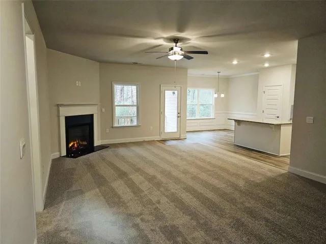 a view of an empty room with chandelier and fireplace