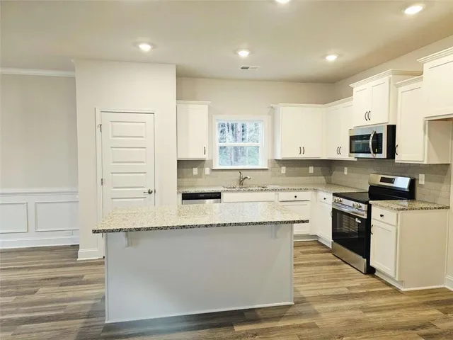 a kitchen with stainless steel appliances granite countertop a stove a sink and white cabinets
