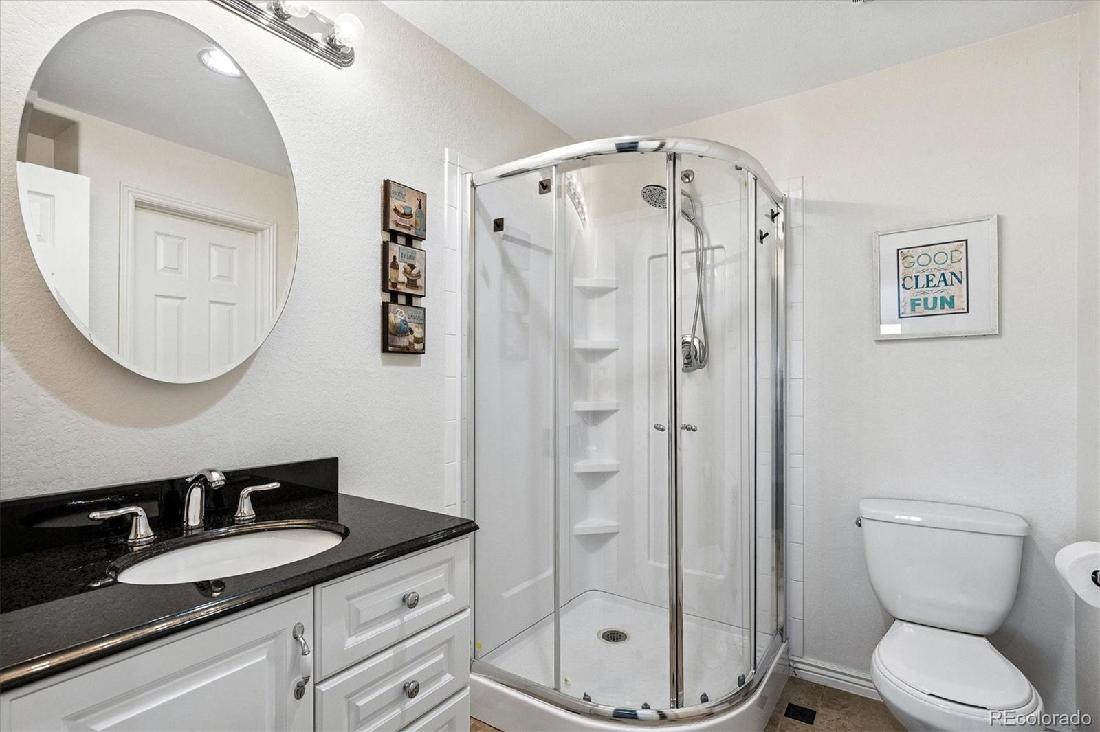 4143 South Deframe Court Morrison, CO 80465 - Photo 43 of 48 a bathroom with a granite countertop sink toilet a mirror and shower