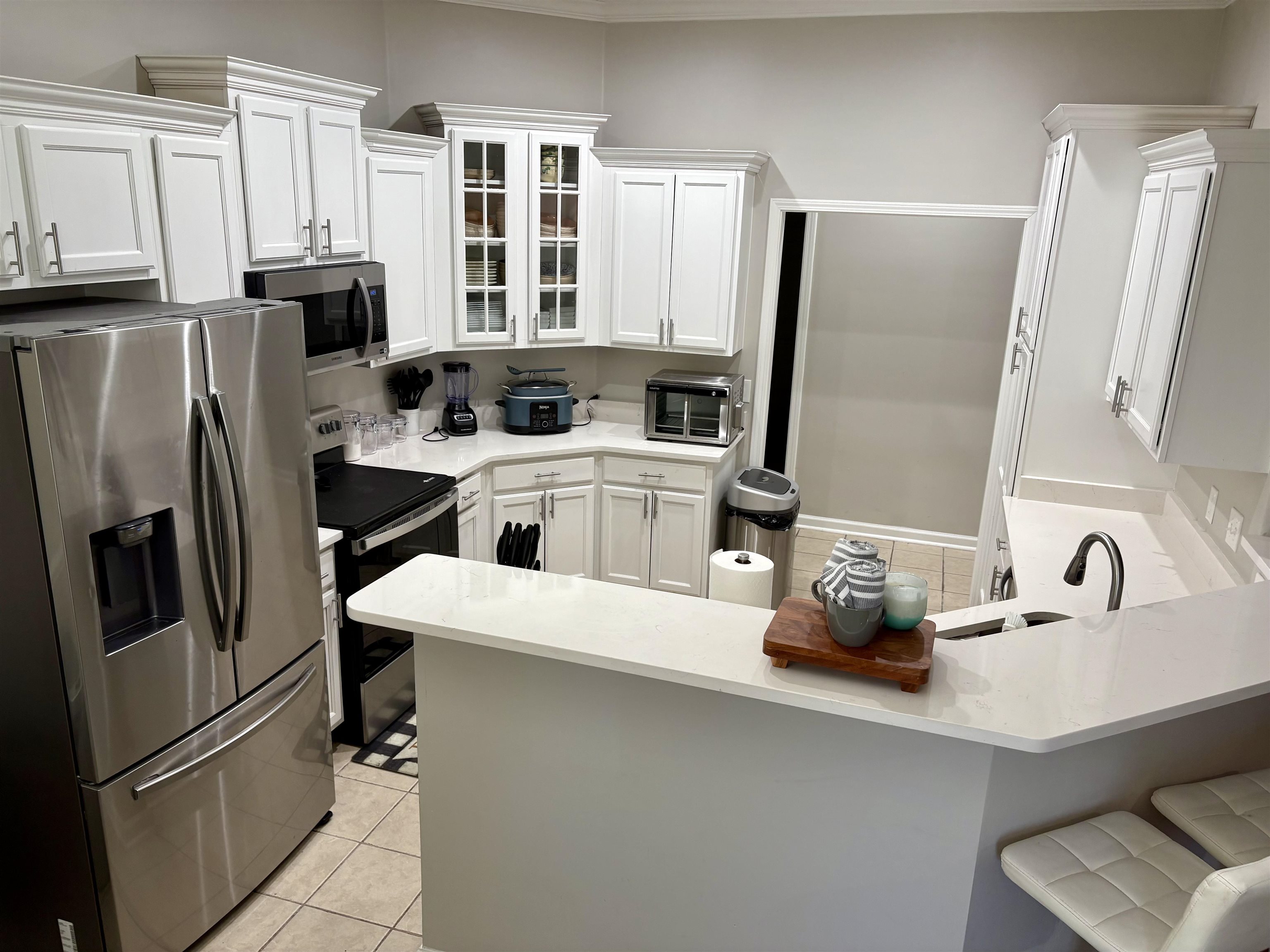 9107 Raspberry Lane Cordova, TN 38016 - Photo 14 of 26 Kitchen featuring stainless steel appliances, glass insert cabinets, a kitchen breakfast bar, white cabinets, and a peninsula