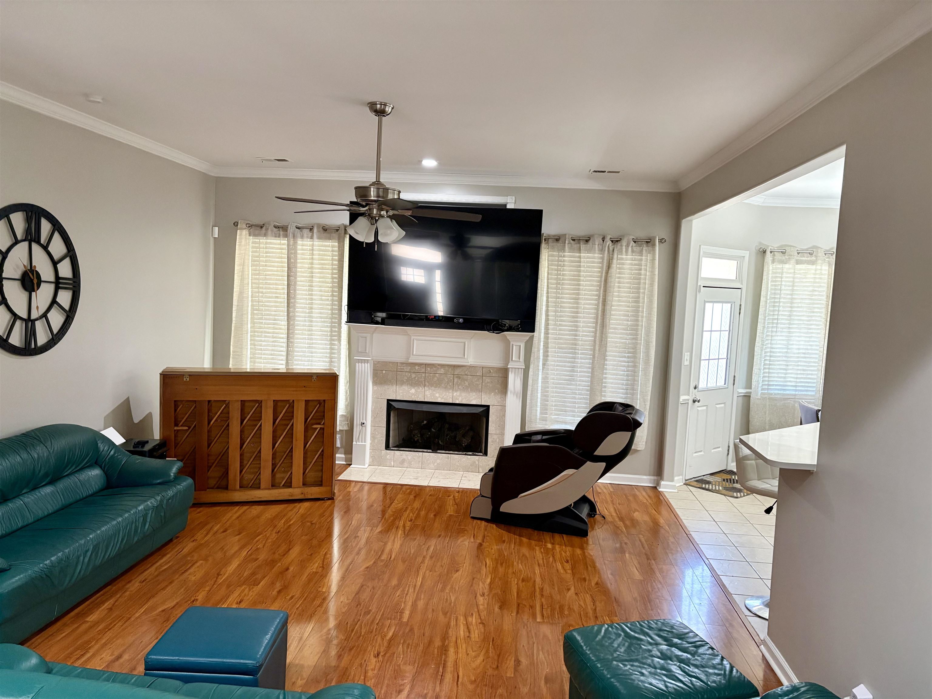 9107 Raspberry Lane Cordova, TN 38016 - Photo 9 of 26 Living room with ornamental molding, wood finished floors, ceiling fan, and a tiled fireplace