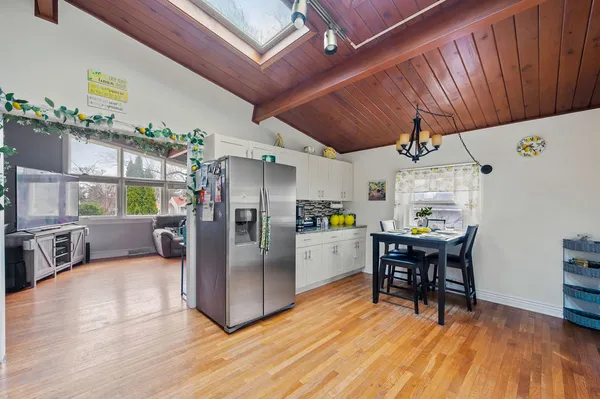 a kitchen with stainless steel appliances a dining table chairs refrigerator and sink