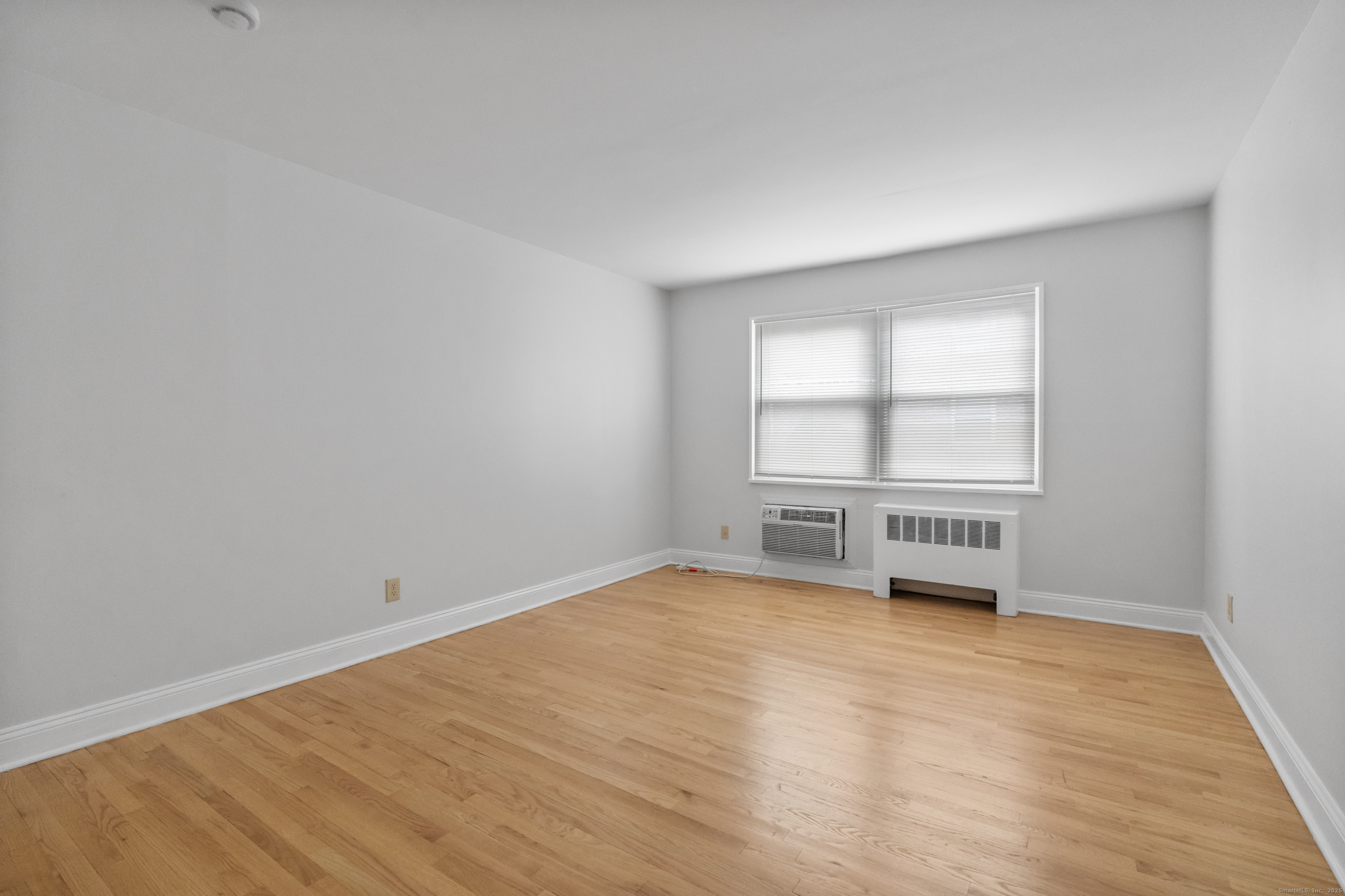 66 Blachley Road, Unit C Stamford, CT 06902 - Photo 12 of 26 an empty room with wooden floor and windows