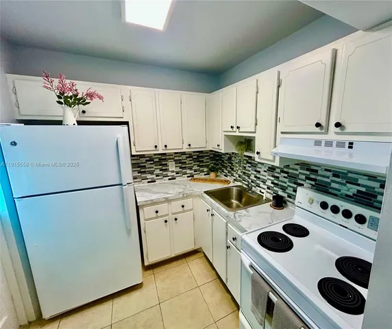 a kitchen with a refrigerator a stove and white cabinets