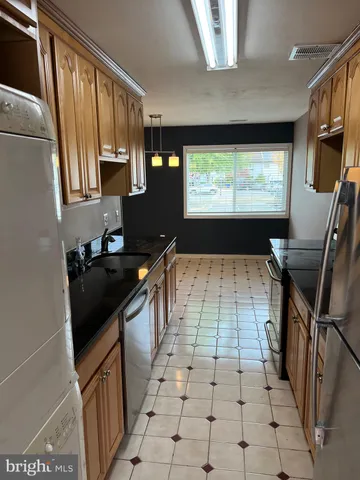 a kitchen with granite countertop a stove a sink and a refrigerator