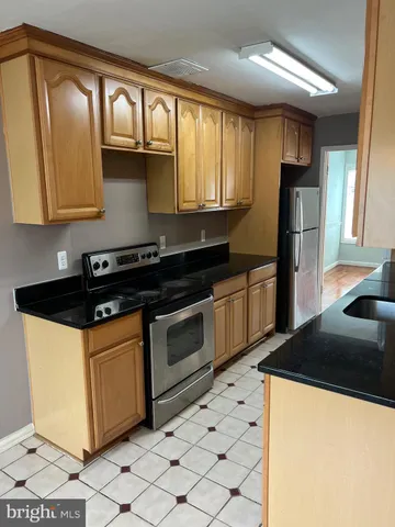 a kitchen with granite countertop a refrigerator a stove and a sink