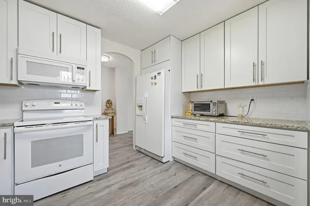 a kitchen with granite countertop white cabinets and white appliances