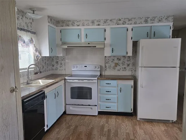 a kitchen with cabinets appliances and wooden floor