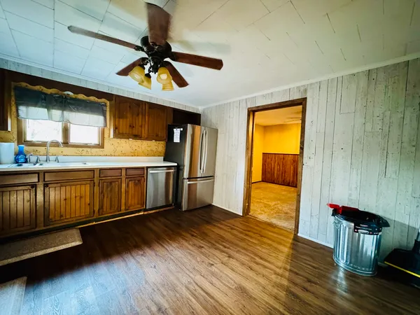 a kitchen with stainless steel appliances granite countertop a stove a sink dishwasher and a refrigerator with wooden floor