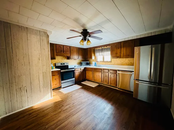 a kitchen with granite countertop stainless steel appliances a stove a sink a refrigerator and cabinets