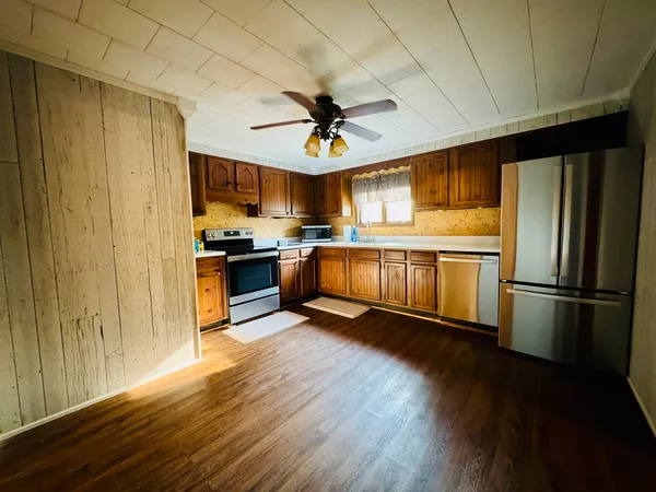 a kitchen with stainless steel appliances granite countertop a refrigerator a stove top oven a sink and dishwasher with wooden floor