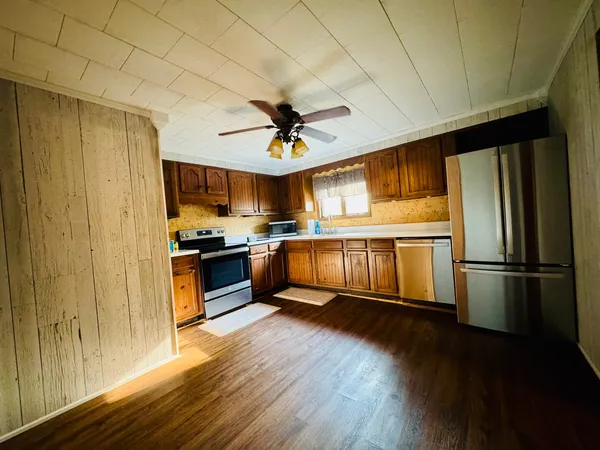 a kitchen with granite countertop stainless steel appliances a refrigerator a stove a sink and a dining table with wooden floor