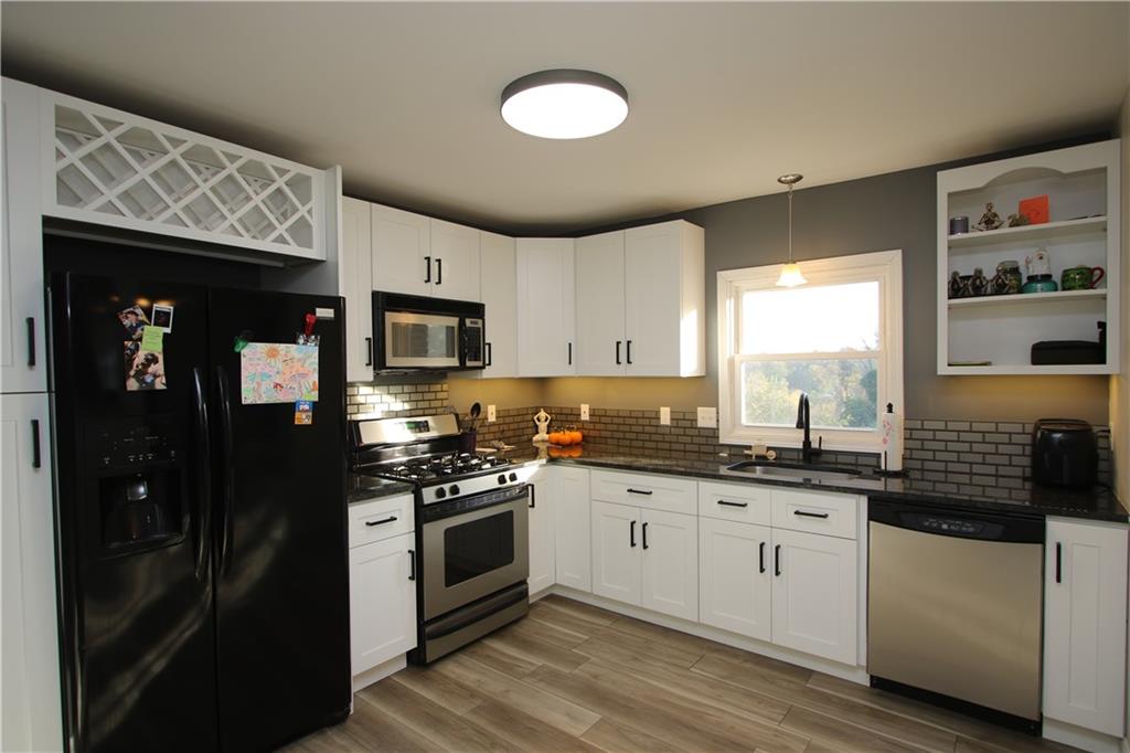 290 Lincoln Hall Road Elizabeth, PA 15037 - Photo 3 of 24 Gorgeous Modern 11x11 Kitchen with Overhead Lighting, Life Proof Hardwood Flooring, Stylish Backsplash, White Wooden Cabinets with Contrasting Hardware, and an Undermount Sink & Granite Countertops.